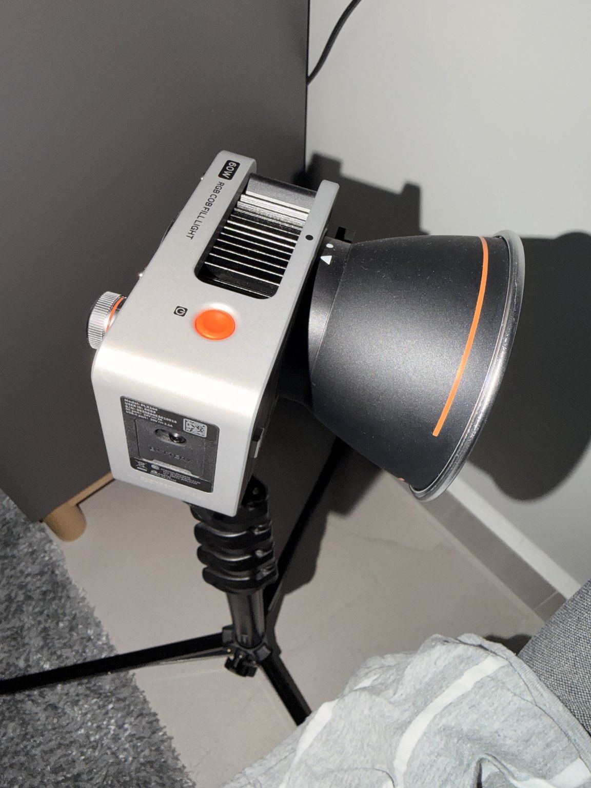 A small lamp with an orange dial on a light stand, set up in the corner of a room.